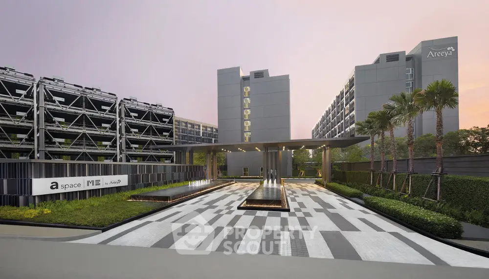 Modern residential complex with sleek architecture and landscaped entrance at sunset.