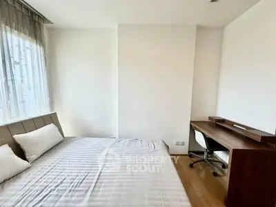 Cozy bedroom with modern desk and natural light, perfect for work and relaxation.