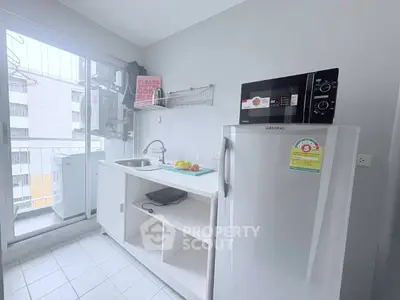 Modern kitchen with compact fridge and microwave, featuring a sleek open layout and balcony access.