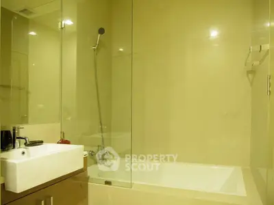 Modern bathroom with glass shower and sleek sink in luxury apartment.
