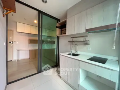 Modern kitchen with sleek cabinetry and glass sliding doors in contemporary apartment.