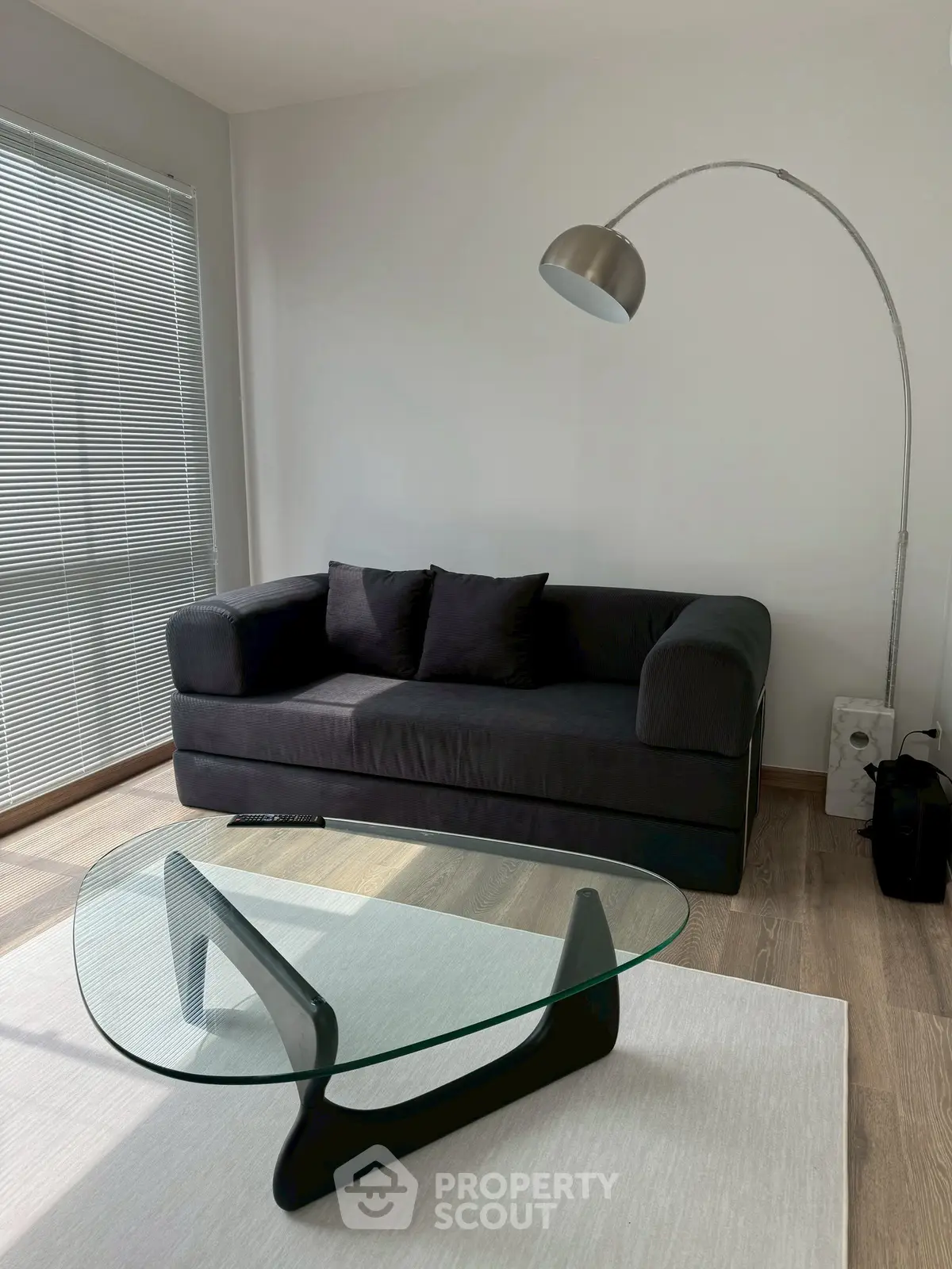 Modern living room with sleek black sofa and stylish glass coffee table, perfect for contemporary urban living.