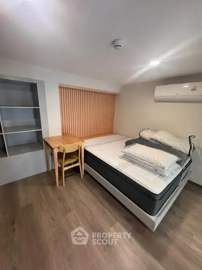 Modern bedroom with sleek design, featuring a comfortable bed, built-in shelves, and air conditioning.