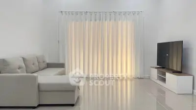 Modern living room with sleek sofa and TV unit, featuring elegant floor-to-ceiling curtains.