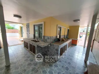Spacious outdoor kitchen with tiled countertops and ample natural light.