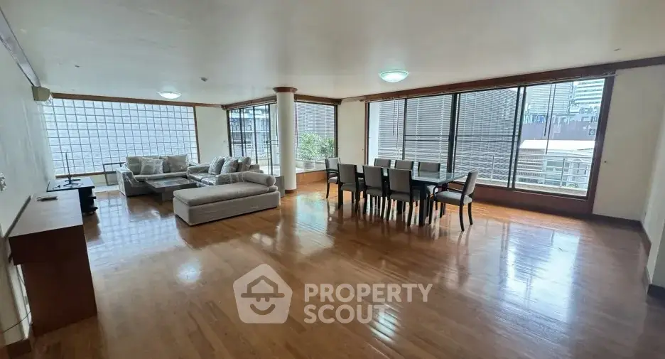 Spacious living room with hardwood floors and large windows in modern apartment.