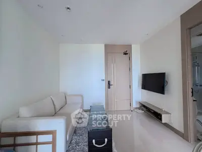 Modern living room with sleek design, featuring a cozy sofa, glass coffee table, and wall-mounted TV.