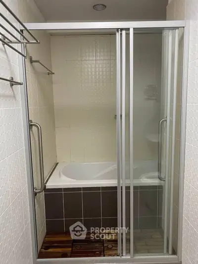 Modern bathroom with glass shower doors and bathtub in a stylish apartment.