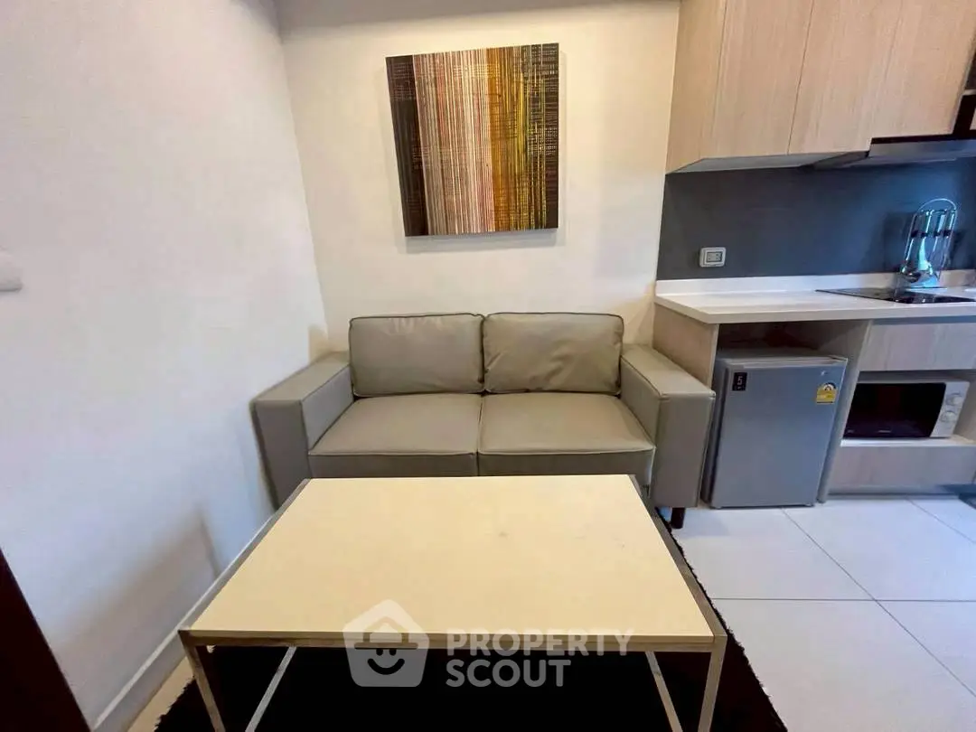Cozy living room with modern sofa and compact kitchen area, perfect for urban living.