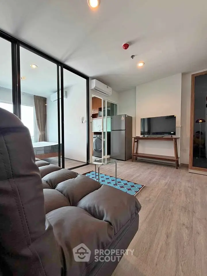 Modern living room with glass partition, sleek furniture, and natural light in a stylish apartment.