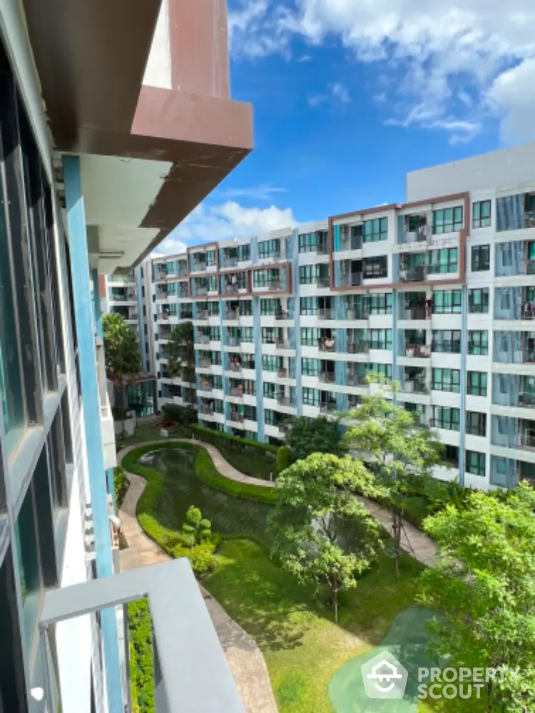 Modern apartment complex with lush green garden and clear blue sky view