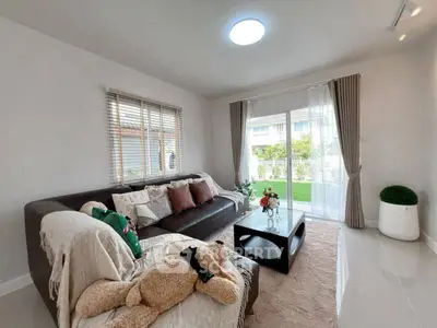 Modern living room with large window and garden view, featuring stylish decor and cozy seating.
