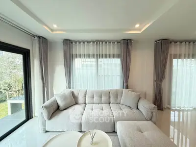 Elegant living room with plush sofa and large windows, offering a bright and airy ambiance.