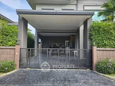 Modern home entrance with gated driveway and lush greenery