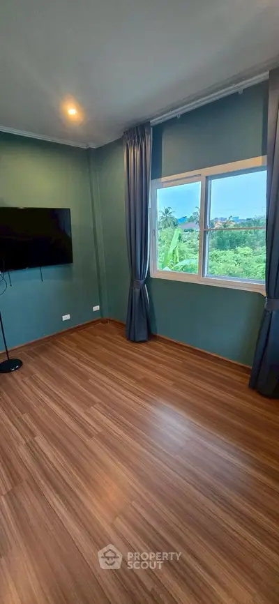 Spacious room with wooden flooring and large window offering scenic views.