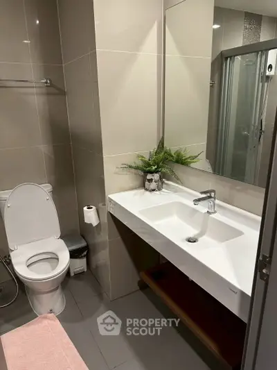 Modern bathroom with sleek fixtures and elegant design, featuring a spacious sink and stylish mirror.