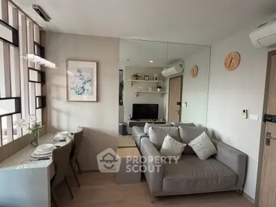 Modern living room with cozy sofa, wall art, and dining area in stylish apartment.