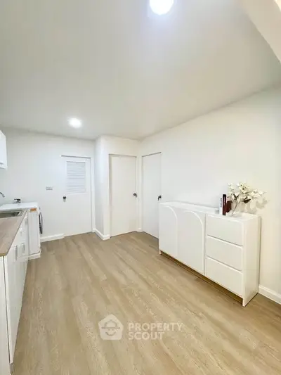 Spacious minimalist kitchen with sleek white cabinetry and wood flooring