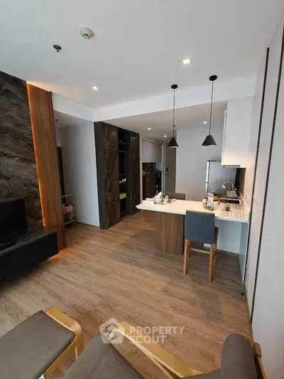 Modern open-layout living room with stylish kitchen and wooden flooring.