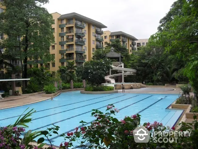 Lush residential complex with a large inviting swimming pool surrounded by vibrant flora and well-maintained facilities, offering a serene oasis for relaxation and recreation.