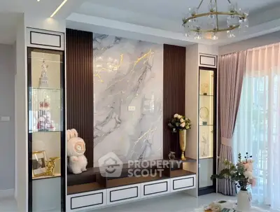 Luxurious living room with elegant marble accent wall and stylish decor, featuring a chandelier and large windows.