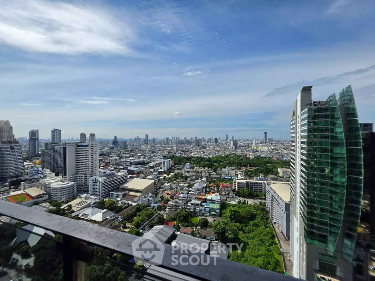 Stunning cityscape view from high-rise balcony with lush greenery and modern architecture.