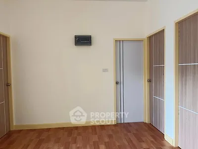 Spacious empty room with wooden flooring and multiple doors, ideal for customization.
