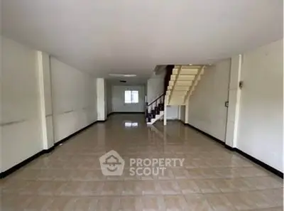 Spacious open-plan living area with tiled flooring and staircase, ideal for customization.