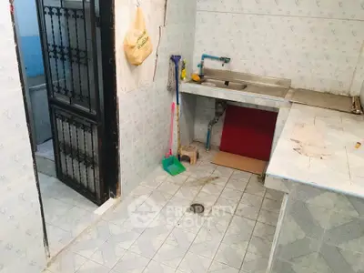 Spacious kitchen with tiled flooring and sink, featuring a closed layout and adjacent bathroom access.