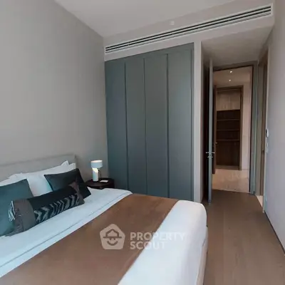 Modern bedroom with stylish decor and ample natural light, featuring a cozy bed and sleek storage solutions.
