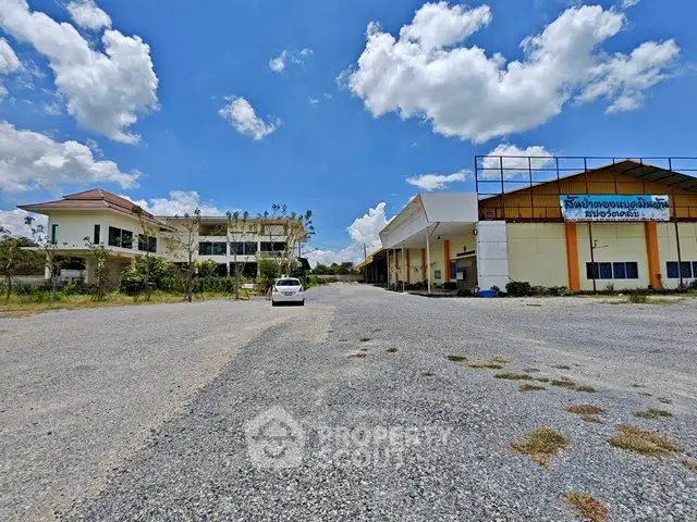 Expansive industrial property with large warehouse and office building under a clear blue sky.