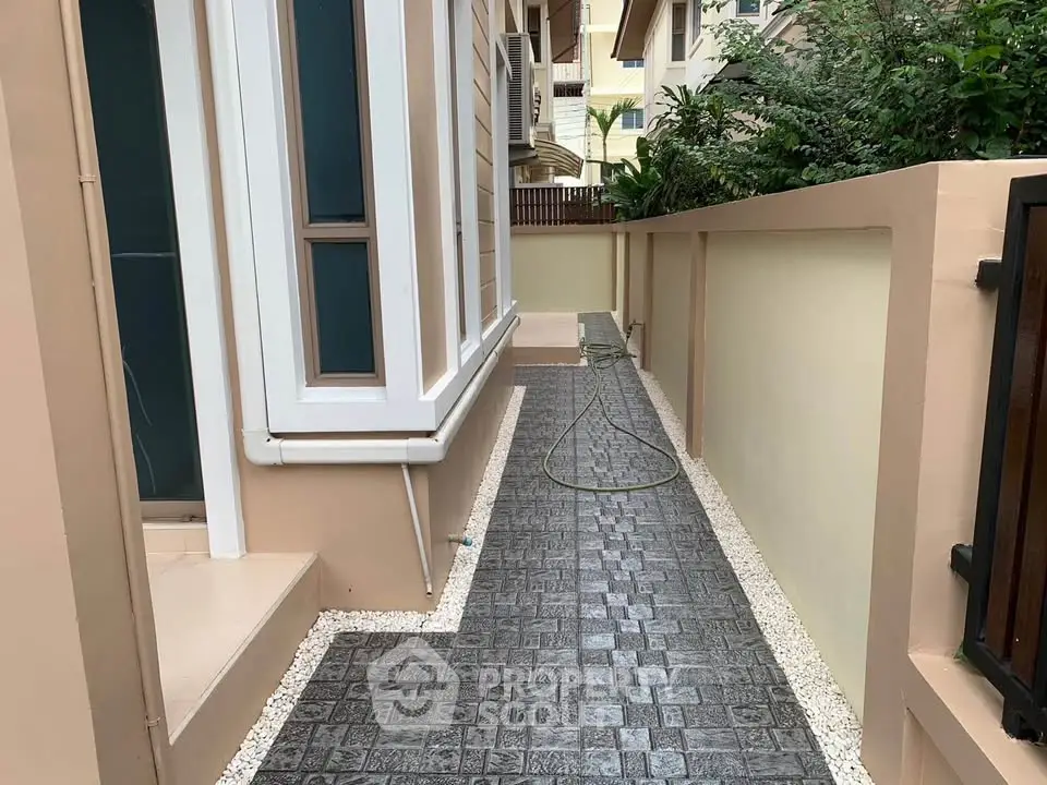 Charming exterior walkway with modern paving and lush greenery in a residential area.
