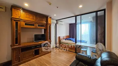 Spacious studio apartment with wooden furniture and glass partition, featuring a cozy bed and entertainment unit.