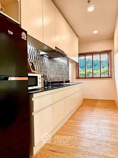 Modern kitchen with sleek cabinetry and large window offering natural light