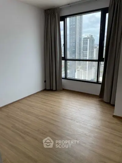 Spacious empty room with large window and city view, perfect for customization.