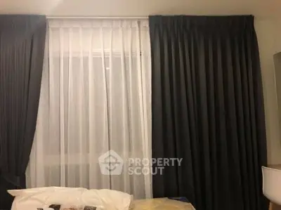 Elegant bedroom with dark curtains and sheer white drapes, creating a cozy ambiance.