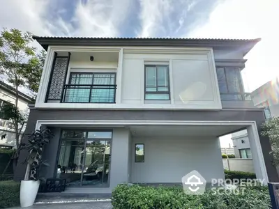 Modern two-story house with large windows and lush greenery