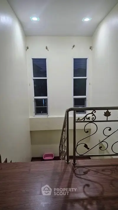 Elegant staircase with decorative railing and large windows in a modern home interior.