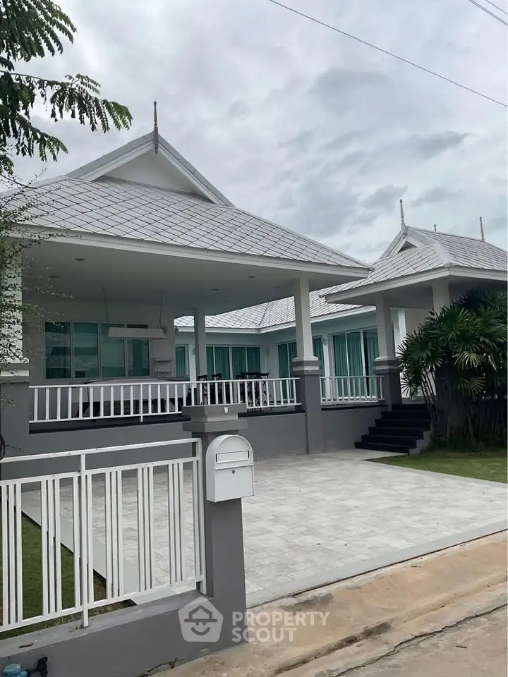 Elegant modern house with unique roof design and spacious driveway in a serene neighborhood.