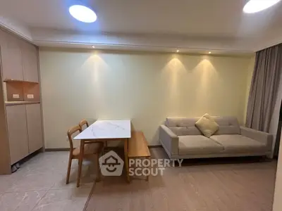 Modern living room with stylish sofa and dining area, featuring elegant lighting and wooden flooring.