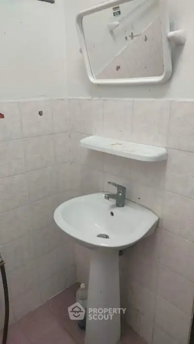 Compact bathroom with pedestal sink and wall-mounted mirror