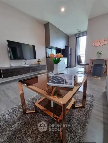 Modern living room with stylish furniture and large TV, featuring elegant decor and natural light.