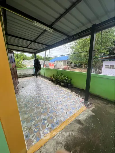 Charming covered balcony with tiled floor and garden view, perfect for relaxation.