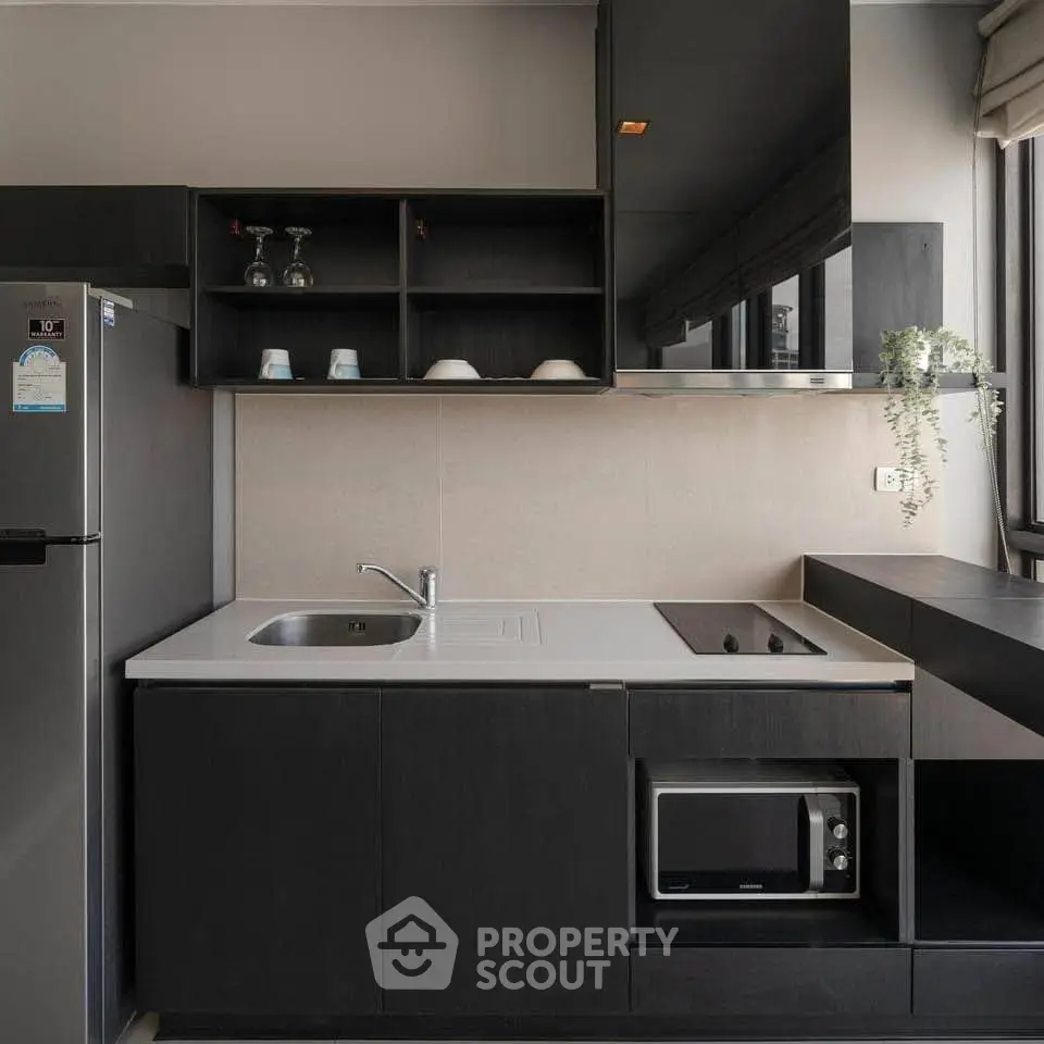Modern kitchen with sleek black cabinetry and built-in appliances, featuring a compact and efficient design.