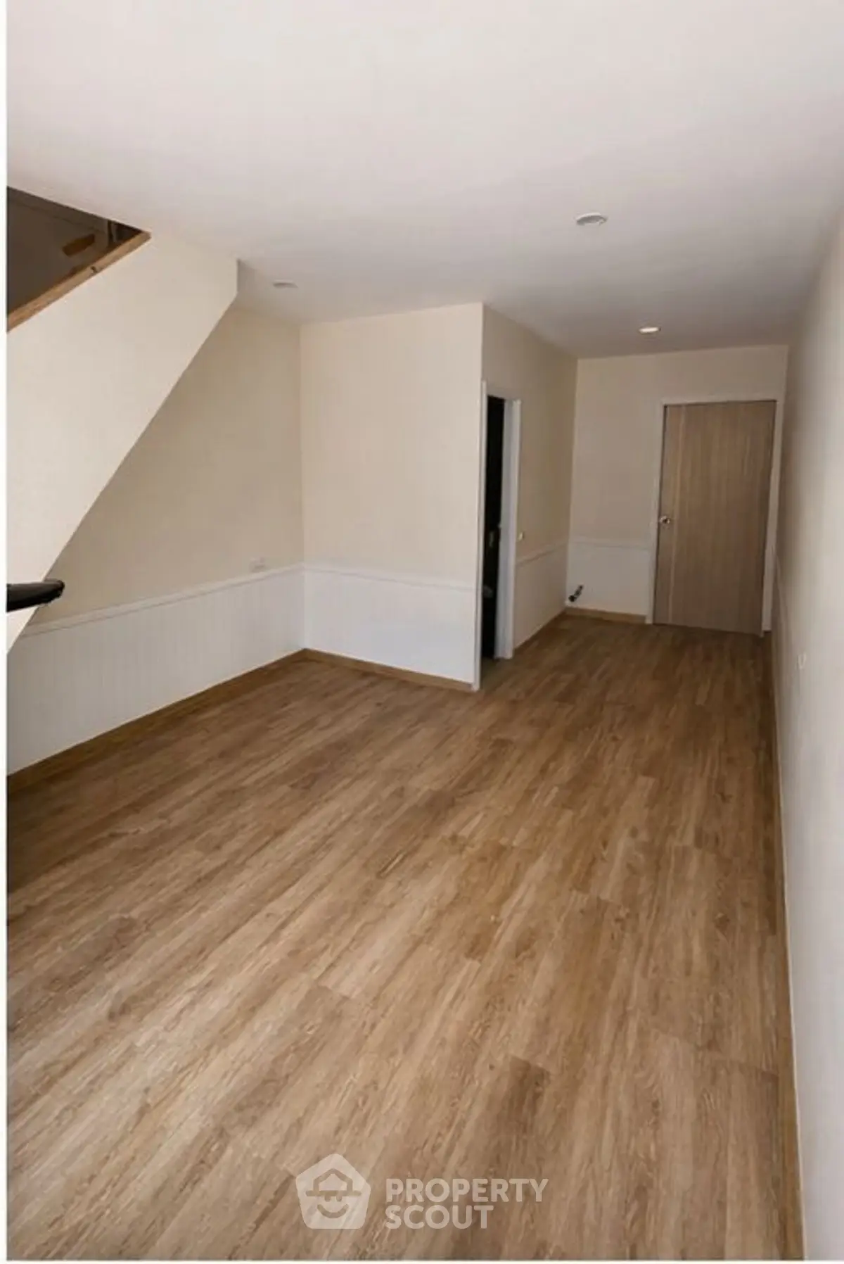 Spacious empty room with wooden flooring and neutral walls, ideal for customization.