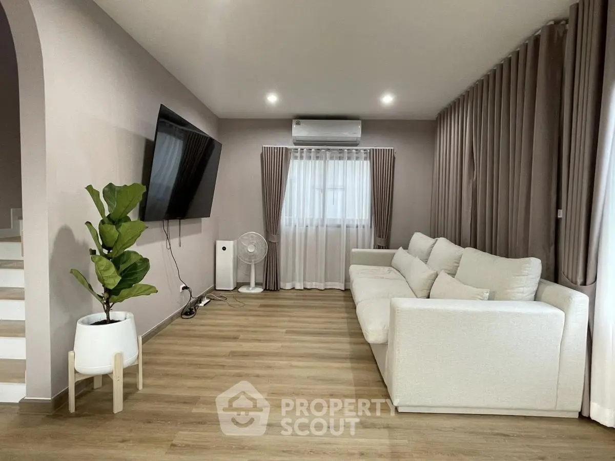 Modern living room with sleek design, large TV, and cozy white sofa.