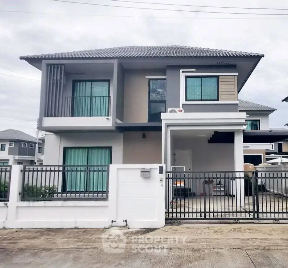 Modern two-story house with sleek design and gated entrance in suburban neighborhood.
