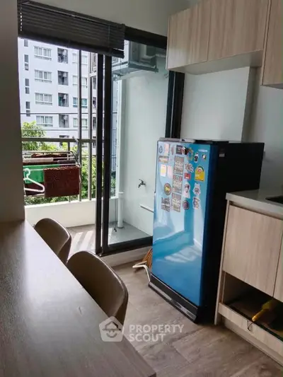 Modern kitchen with blue fridge and balcony access in urban apartment.