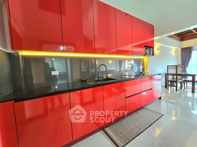 Modern kitchen with sleek red cabinets and black countertop in a stylish apartment.