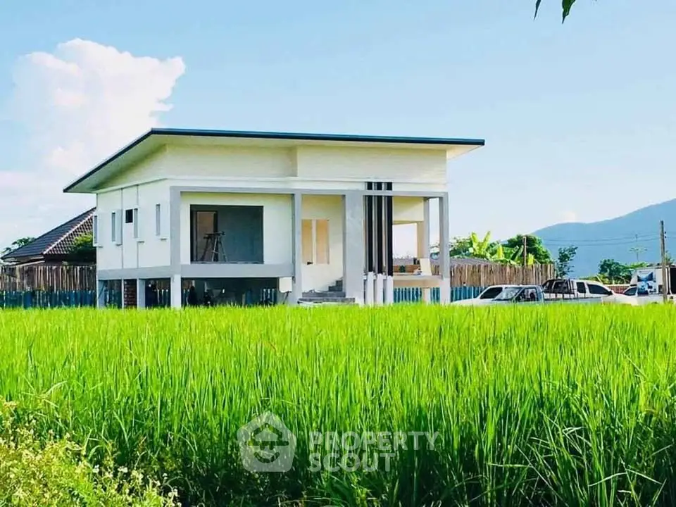 Modern elevated house with lush green field and mountain view, perfect for serene living.